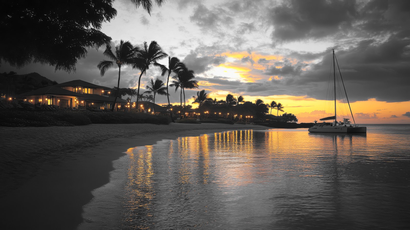 A Florida Keys shore at dusk — a lamplit house among palms and a sailboat at anchor